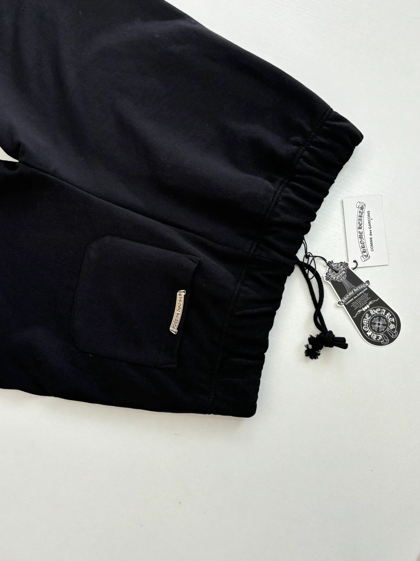 P346 Chrome Hearts*/Chrome Hearts 26SS early spring new patch embroidered shorts The fabric is made of a blended ratio of 80% cotton and 20% polyester. It is woven with a siro spinning process of 32-count base yarn and 10-count veil to form a high-weight terry cloth base of 380g/㎡. The cotton-polyester blended material combines the skin-friendly breathability of cotton and the anti-wrinkle shape retention of polyester. The high-weight fabric gives the trousers excellent stiffness and drape. The core technology is patch embroidery, which is completed with the help of TAJIMA computer embroidery machine. The black special-shaped patch is precisely sewn to the trouser fabric through lock stitches. The embroidery stitch density is even and the edges are neatly hemmed, forming a three-dimensional relief-like visual effect. Size: S/M/L/XL